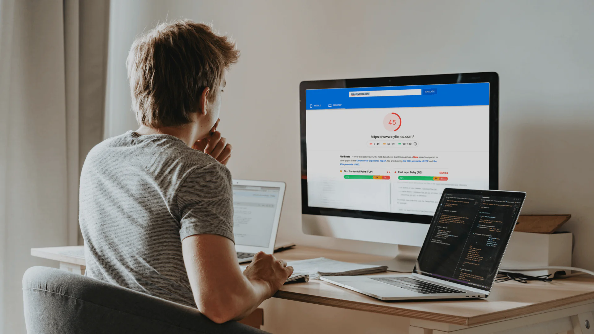 Person analyzing website speed optimization on multiple devices with PageSpeed Insights showing a low score