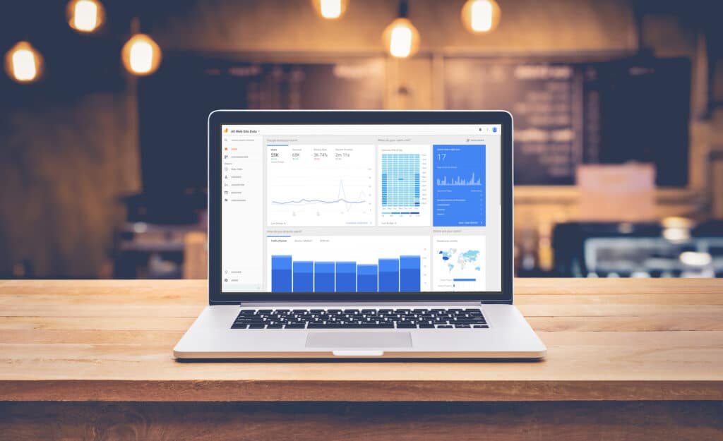 Tech blogger's laptop displaying Google Analytics dashboard with blog traffic metrics and visualizations in a cozy workspace
