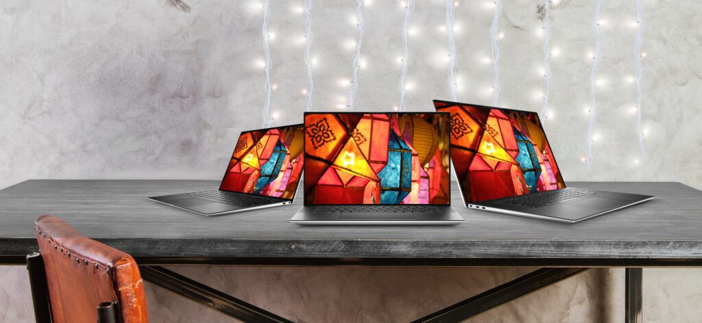 Three laptops on table displaying colorful lantern images with festive background lighting
