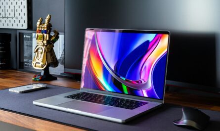 Modern desk setup with laptop, smartphone, mouse, and LEGO Infinity Gauntlet in tech-savvy workspace